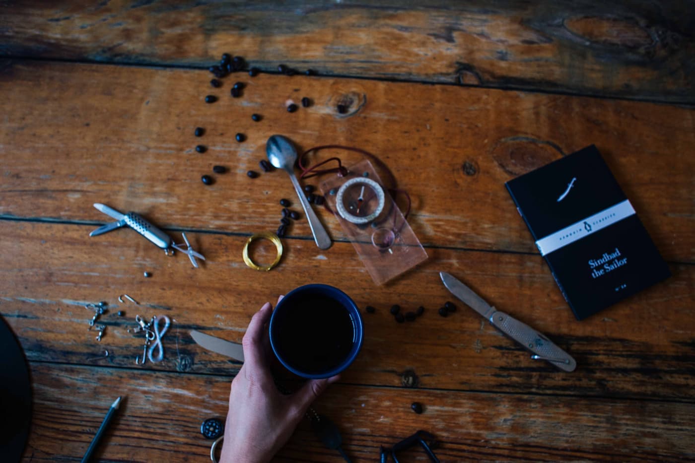 Pocket tools and a folding knife laid out on a dark wooden table
