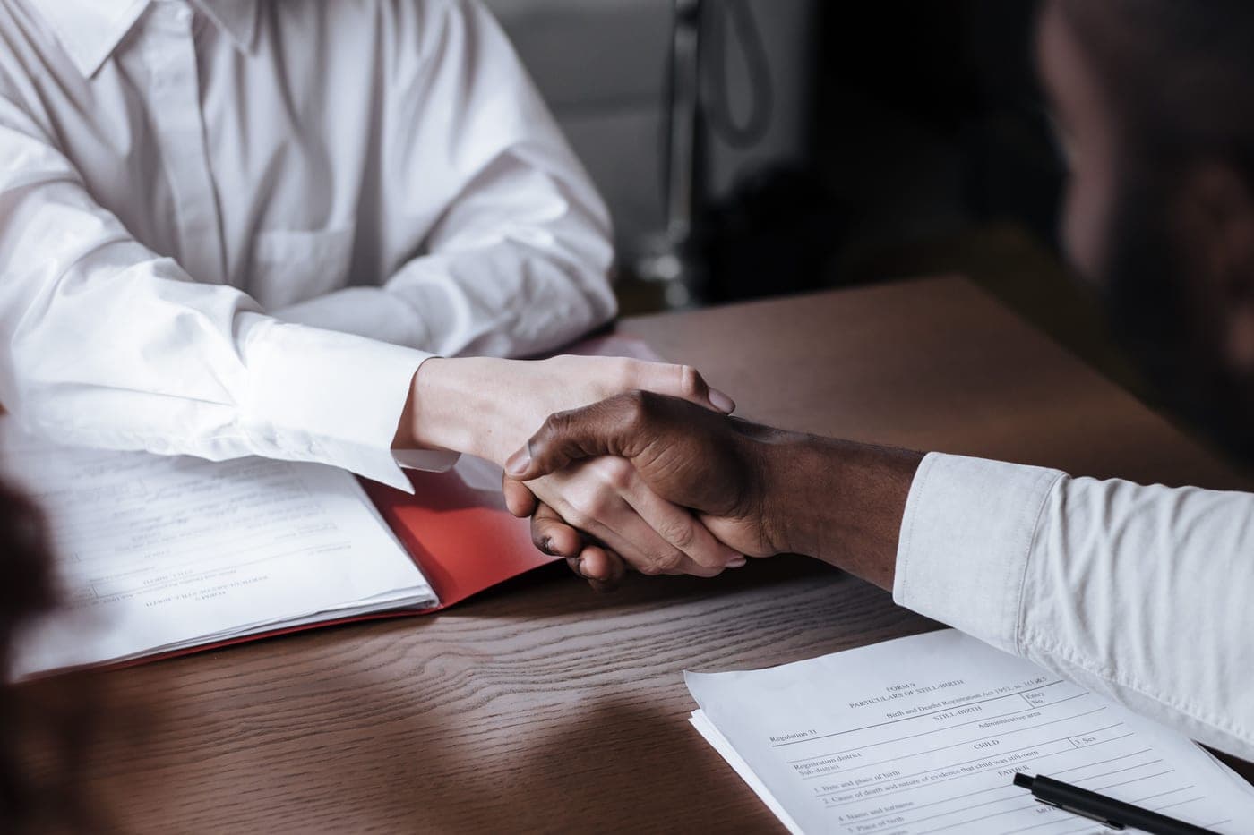 Two people shaking hands across a desk