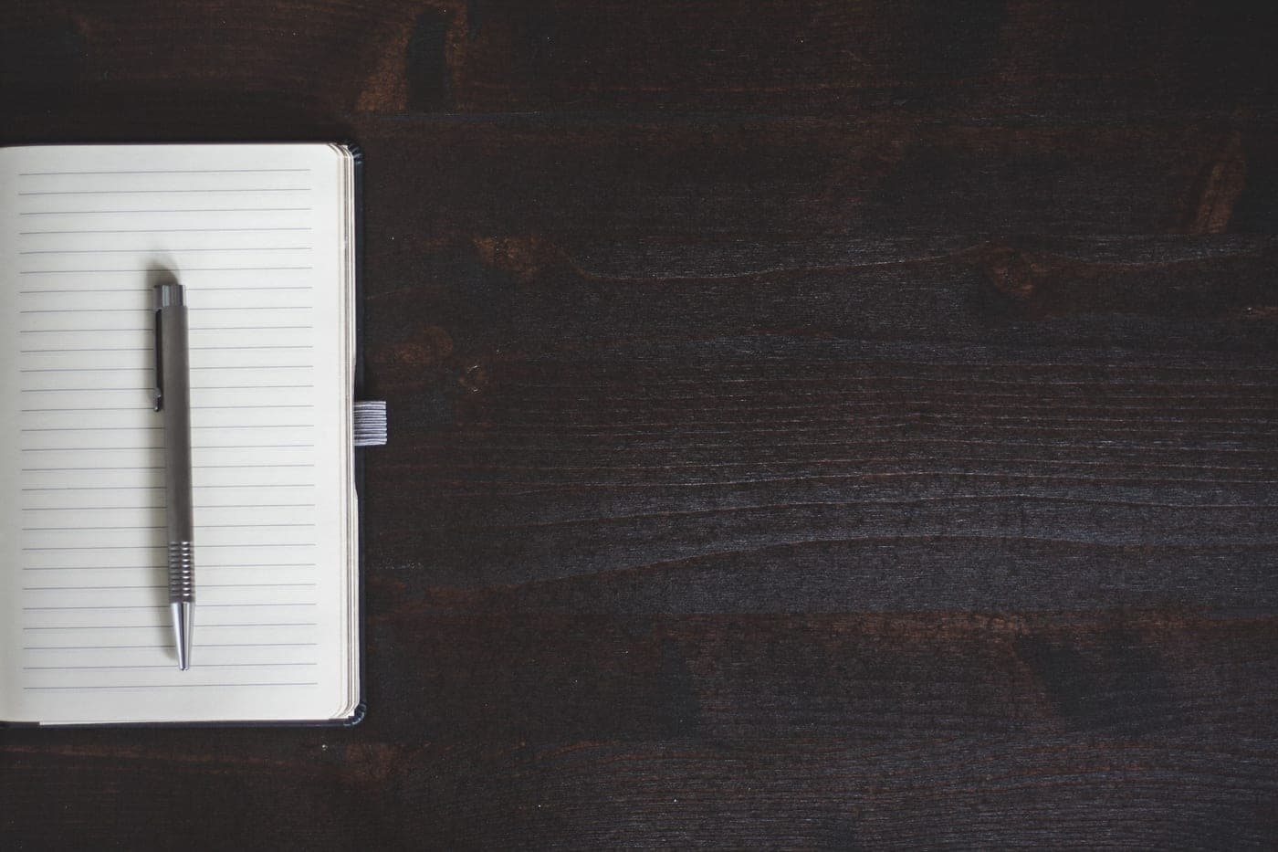 A ledger notebook and pen on a dark desk