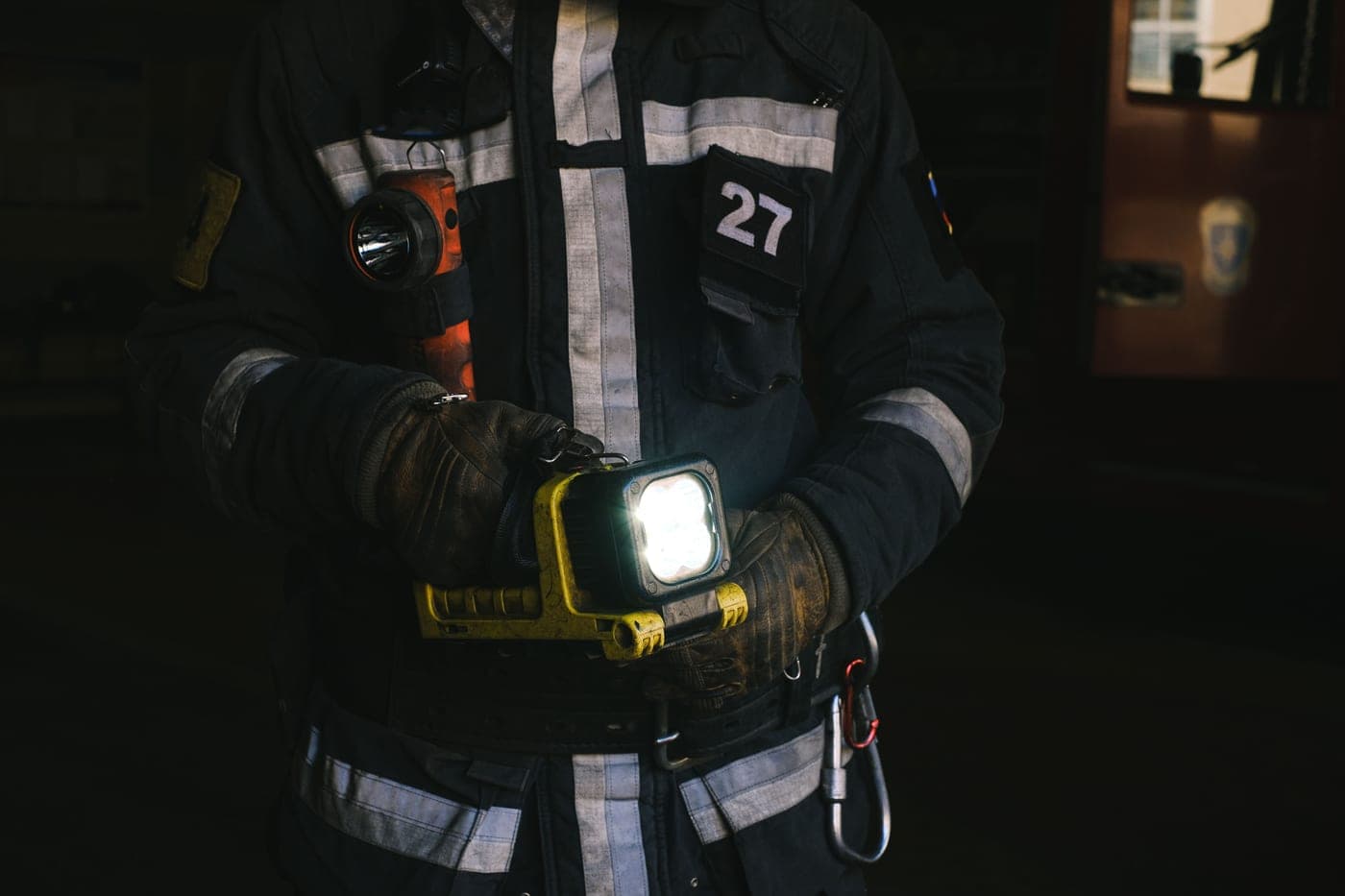 A firefighter in full protective clothing holding a lantern