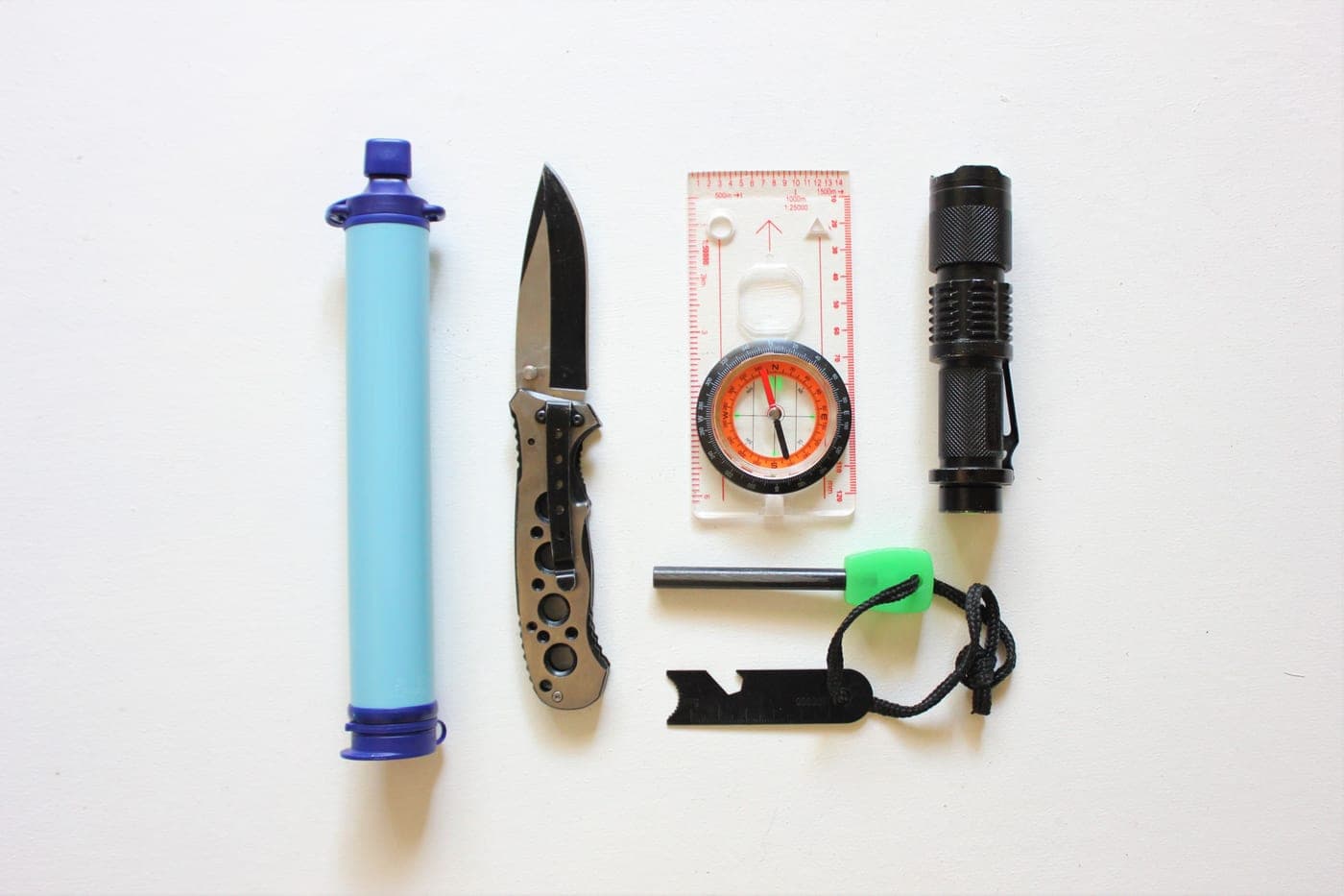 A flat lay of survival kit items on a white background