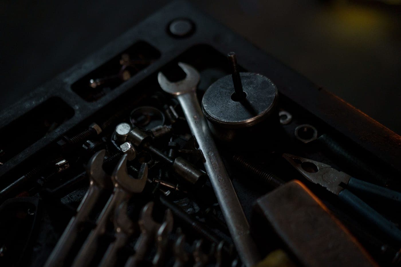 Assorted hand tools and wrenches on a workbench in a dimly lit workshop