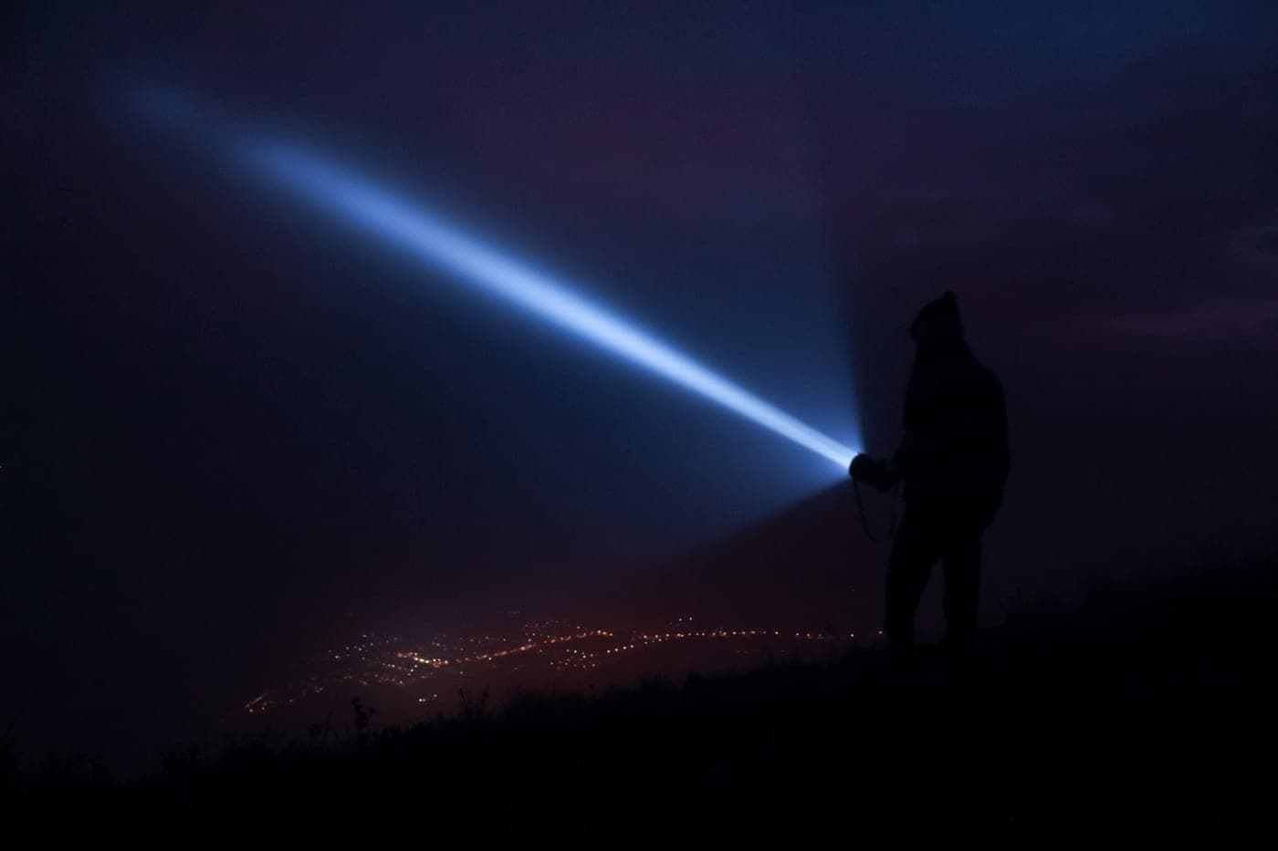 A flashlight beam picking out a dark path at night