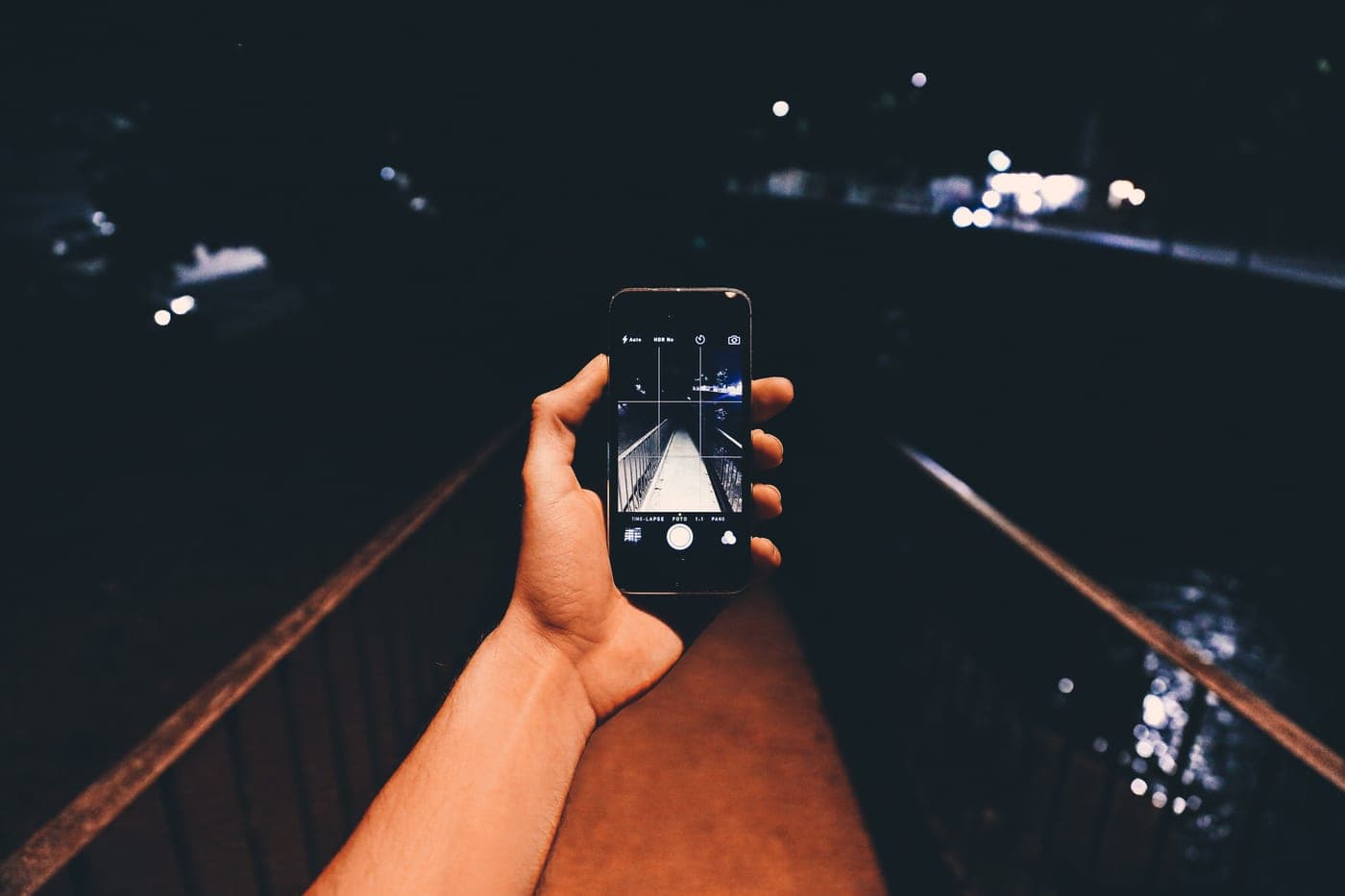 A hand holding a lit flashlight against a dark background
