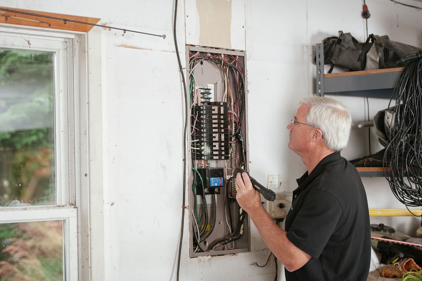 Someone examining a residential fuse box by torchlight