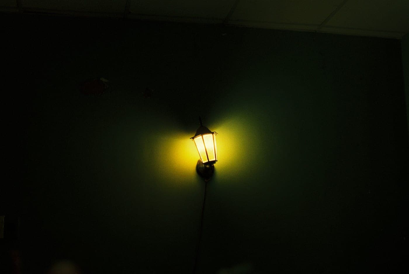 A single wall lantern glowing warmly against a dark wall