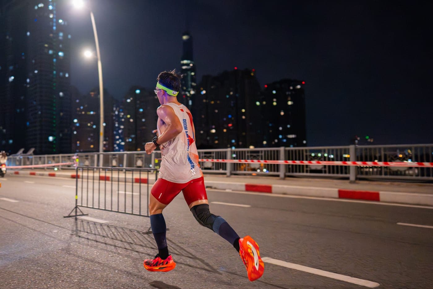 A runner wearing a head torch on a dark trail