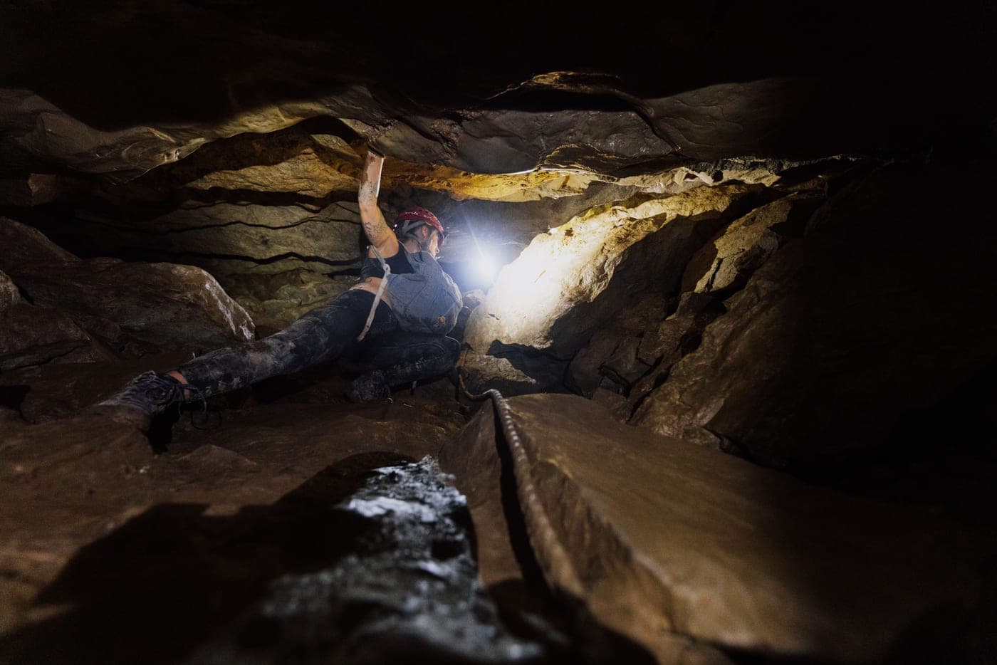 A climber wearing a headlamp inside a dark cave