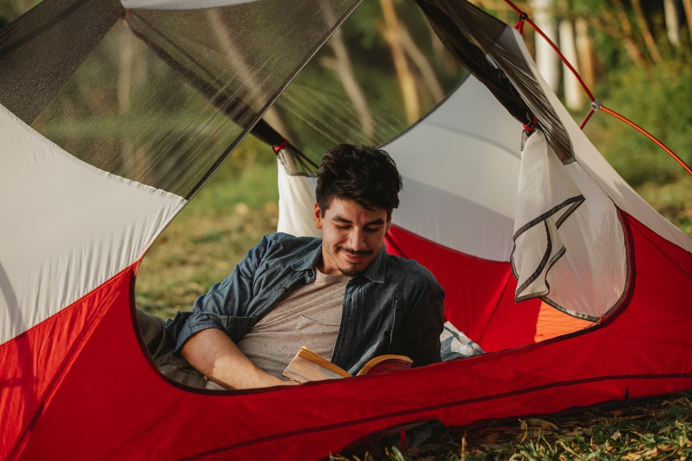 A camper reading inside a lit tent at night