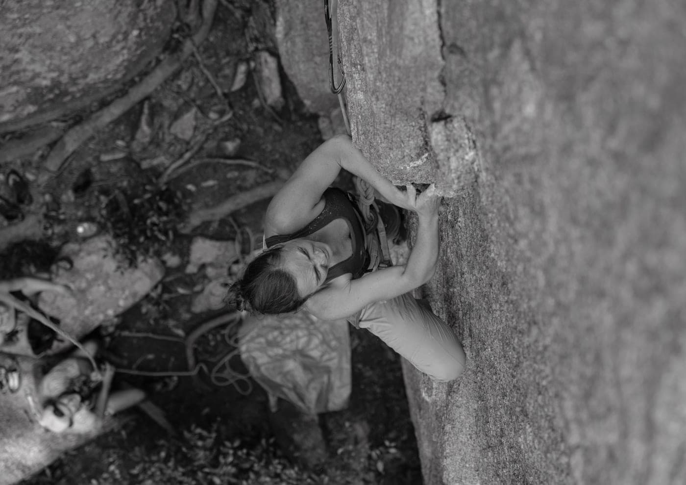 A climber on a rock face photographed from above in black and white