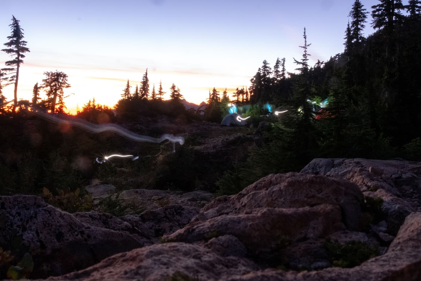 Tents and lights glowing under a mountain sky at dusk