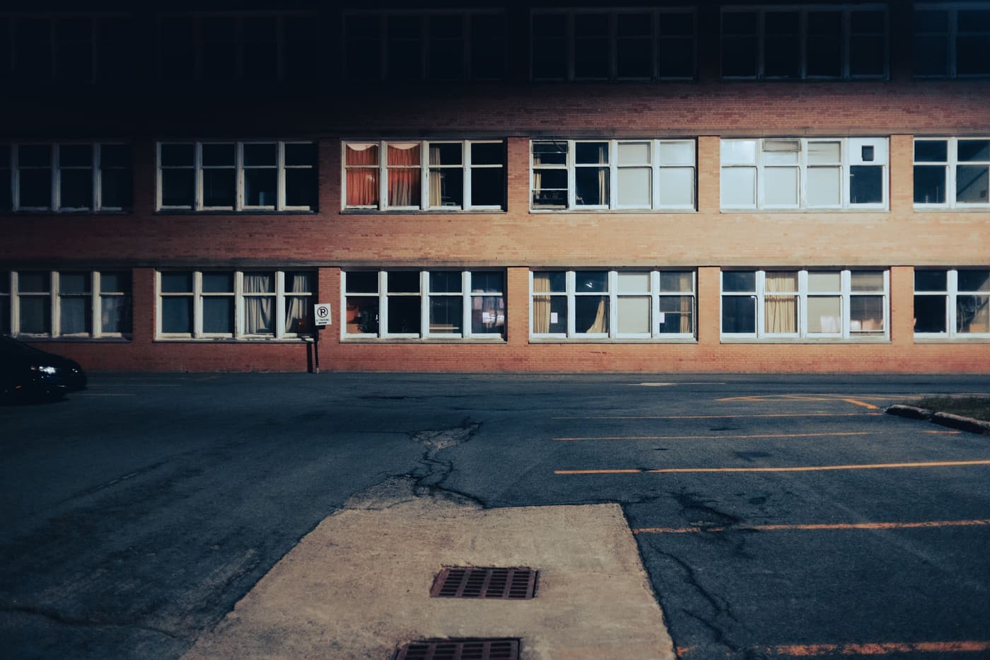 An empty parking lot beside a brick building at night