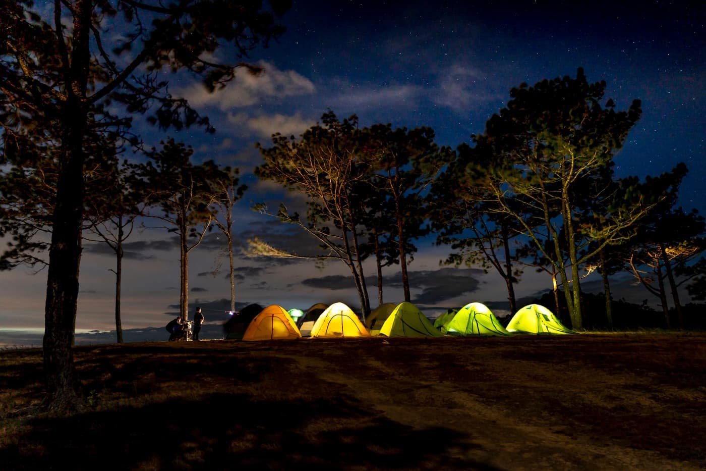 A tent glowing from within at a campsite at night
